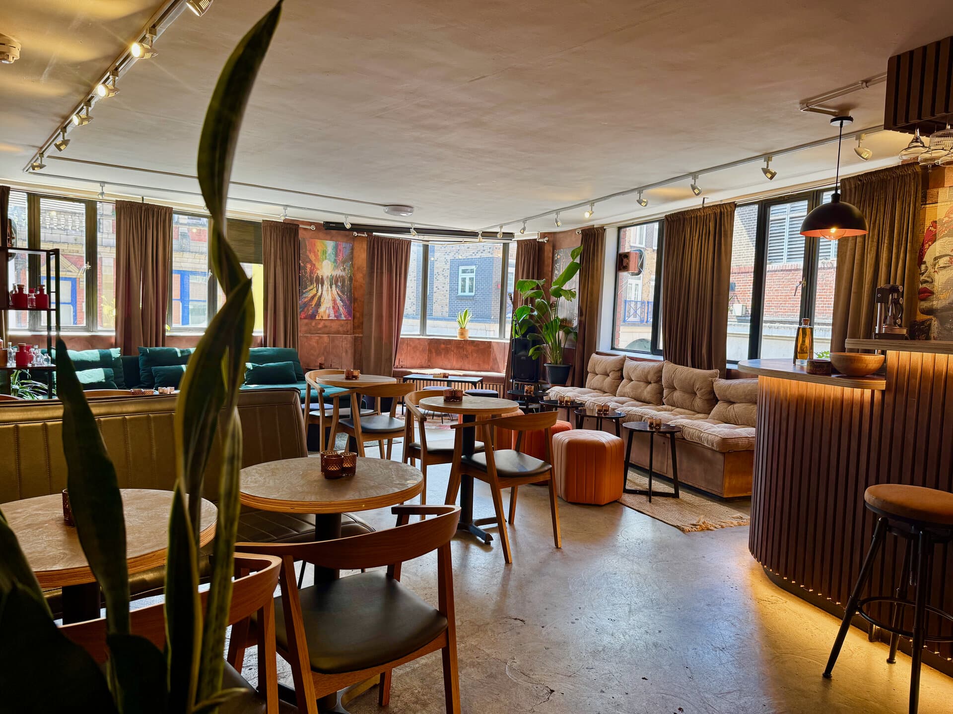 The BCC Distillery daybar — green sofa, tan banquettes, sunlit